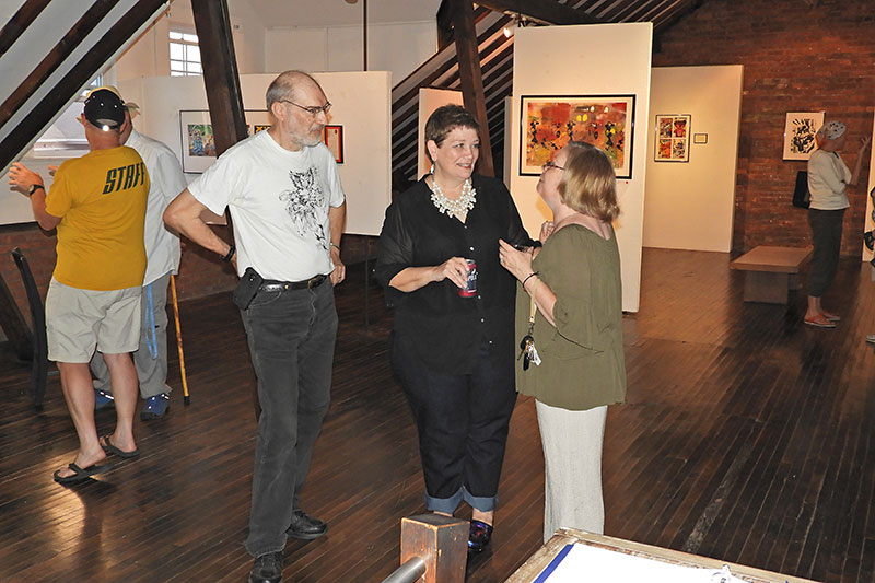 UNY Oswego graduate student Suzanne Beason (center) and her husband, Kirk (left), speak with visitors