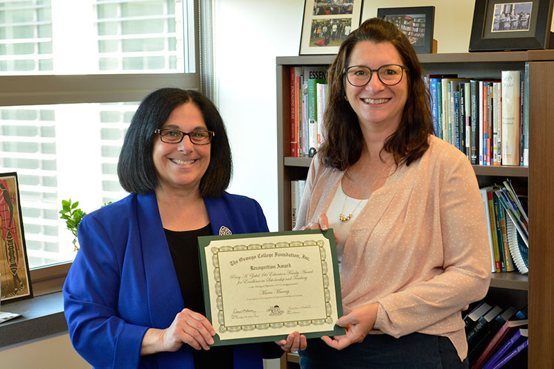 Maria Murray and School of Education Dean Pam Michel display Murray's Perry A. Zirkel Award for teaching