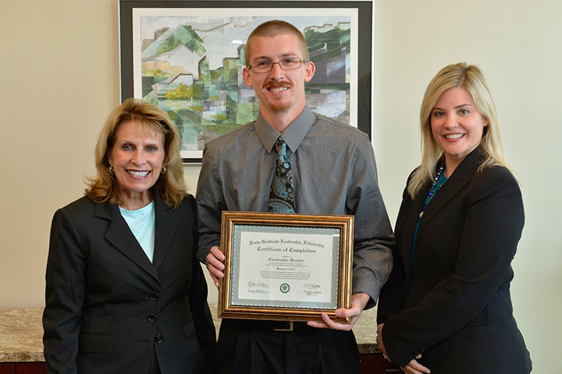 President Deborah F. Stanley and Graduate Studies Dean Kristen Eichhorn recognize graduate student Christopher Bartlett