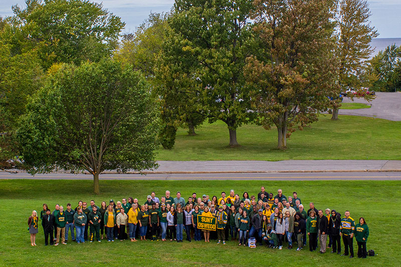 Members of the campus community pose in green and gold