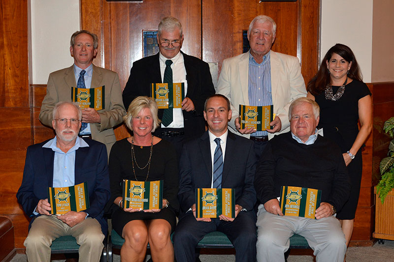 Newest members of athletic hall of fame (or representatives) stand with programs