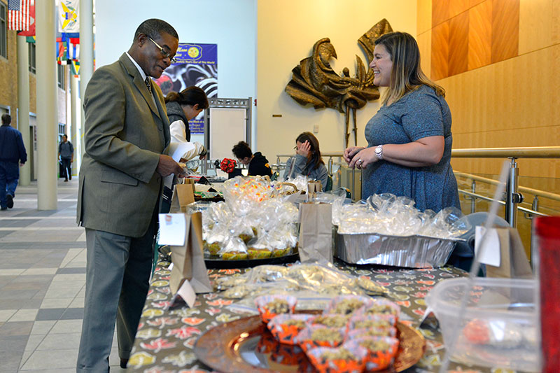 Howard Gordon buys desserts from Shelly Sloan at a table full of goodies