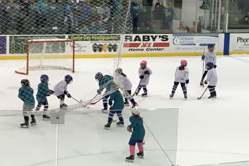 Oswego youth players vie for the puck during a between-periods mini-game