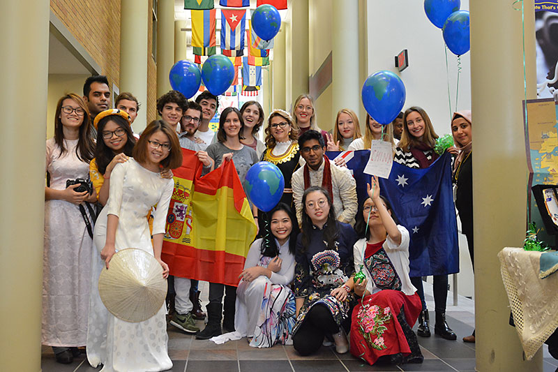 Group photo of international students, many dressed in clothes representing their culture