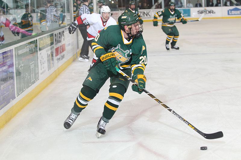 Men's hockey player Max Novick skates with the puck