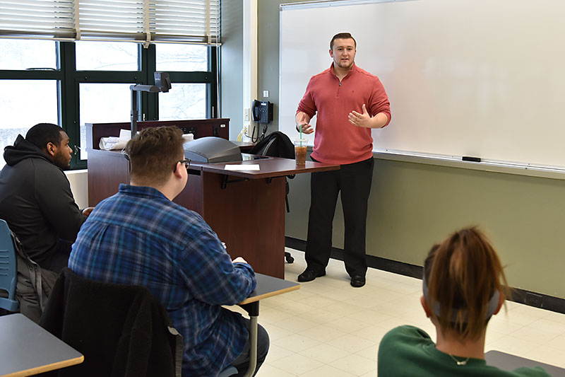 Tucker Sholtes, an alumnus now an advisory associate at PwC/PricewaterhouseCoopers, speaks with communications class