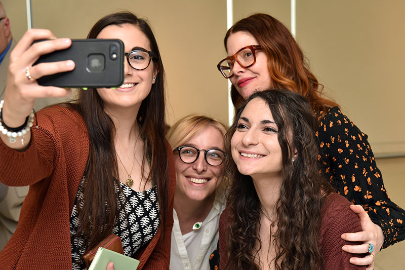 1991 alumna Christene Barberich poses for a selfie with graphic design students 