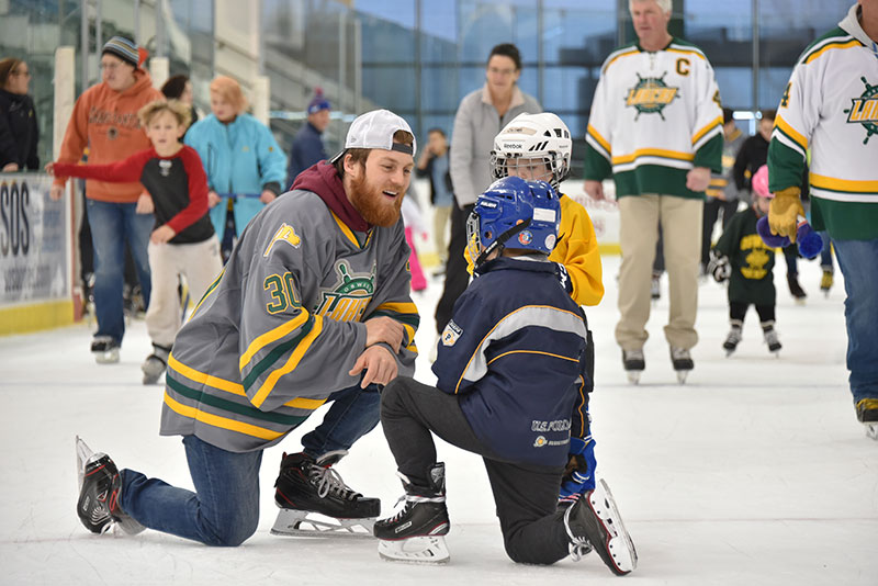 Cedric Hansen of the Laker men's hockey team talks with young skaters