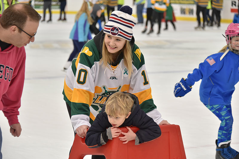 Women’s hockey player Eryn Stewart helps a young skater