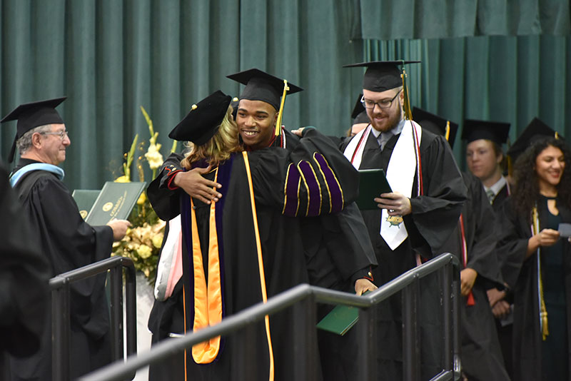 Lamont Sadler hugs college President Deborah F. Stanley during the presentation of diploma