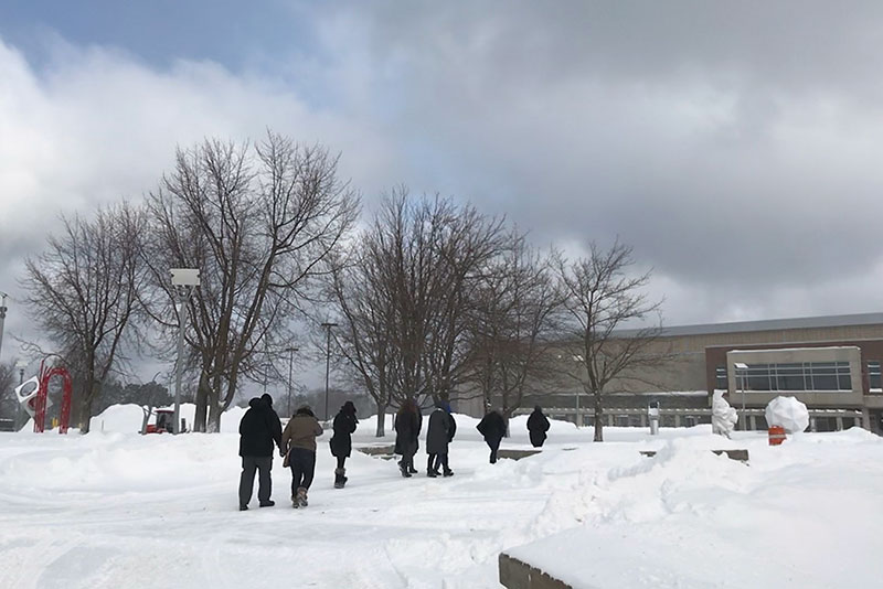 A group touring the campus with a snowscape around them