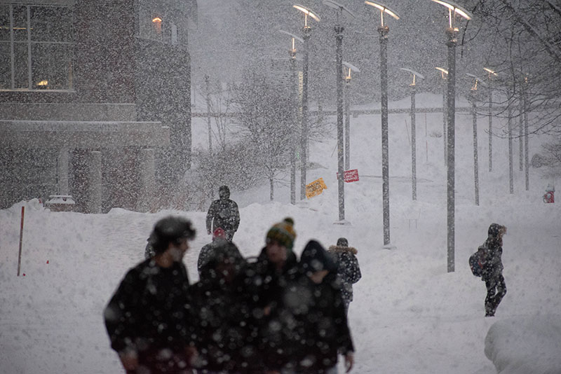 Students walk through falling snow on campus