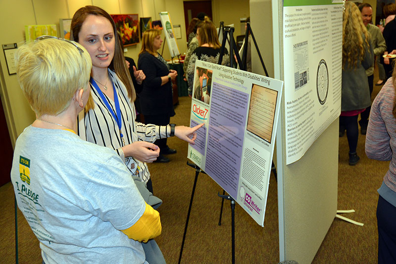 Graduate student Megan Russell explains her research on assistive technologies in the classroom to Mary Toale