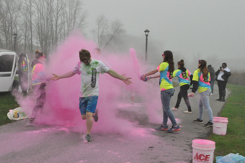 A runner gets sprayed with pink powder as they finish Color Oswego