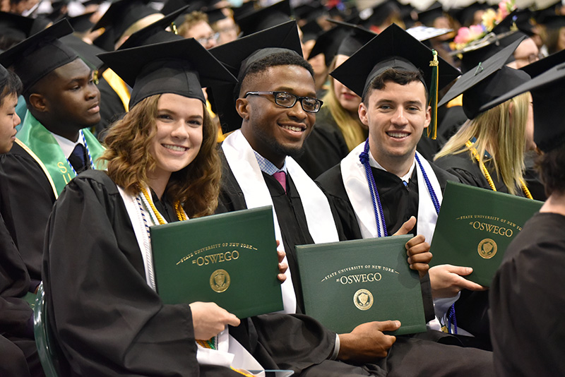 New graduates (from left) Rachel Meyer, Akim Cadet and Colin Maggiolo celebrate after the the 9 a.m. Commencement ceremony