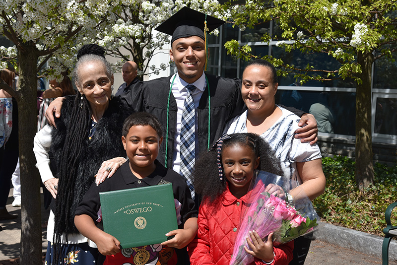 Family members gather around mathematics major Darryl Gomez-Lewis to celebrate his big day following Commencement