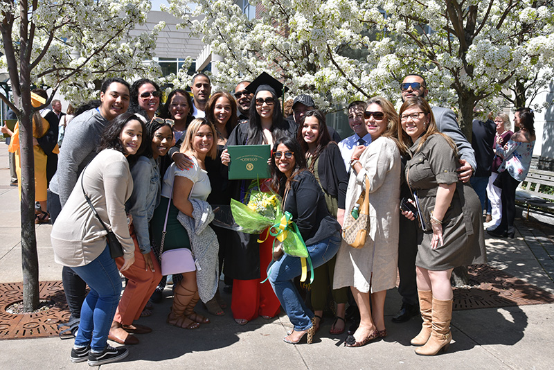 Human development major Desiree Pedrosa (center, in cap and gown) enjoys considerable support for her graduation achievement