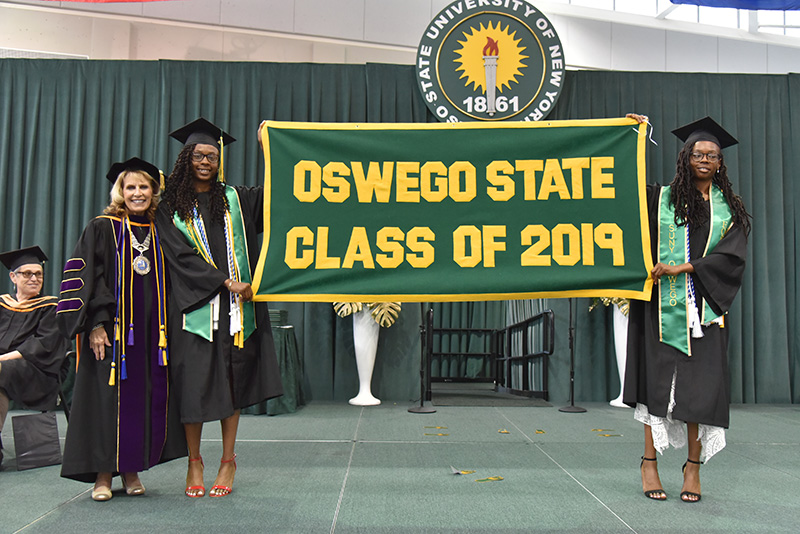 Campbell twins with President Deborah F. Stanley and Class of 2019 banner