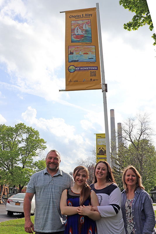 Gianna Ellingwood (second from left), a sixth-grader at Charles E. Riley Elementary School, celebrates her art's inclusion in the My Hometown Banner project with her parents and teacher