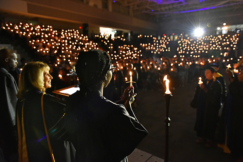 Platform party lifts candles, as does the audience, during Welcoming Torchlight Ceremony