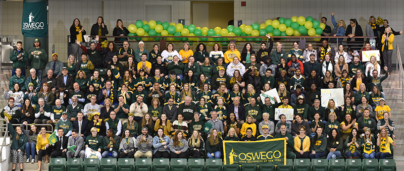 Campus community members in a large group wearing green and gold