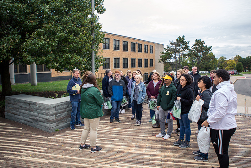 Student tour guide Corey Cesare leads a group near the east entrance of Marano Campus Center facing the Shineman Center during the first Fall Admissions Open House of the year