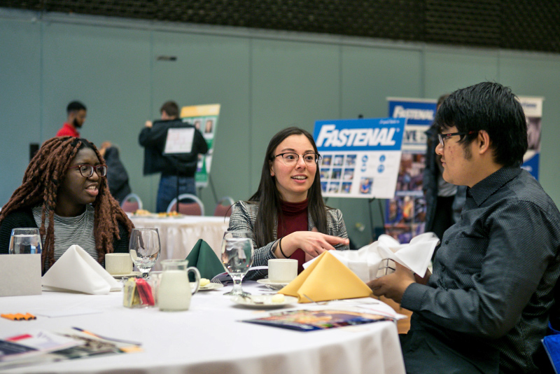 Taeko Kelly of the Career Services Office makes conversation with students Alikeju Adejo (left) and Phone Paing at the Fall Etiquette Dinner