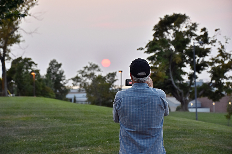 An area resident and 1974 Oswego alumnus captures the sunset with camera and tripod Sept. 16 as it sets over Marano Campus Center.