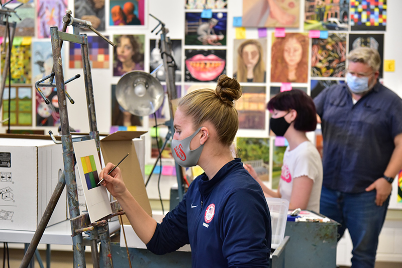 Malia Minckler (foreground), a senior art/illustration major, works on a painting during a painting class taught by Christopher McEvoy. In the background, Kate Miller, a sophomore art/graphic design major, gets some feedback from McEvoy.