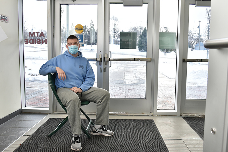 Jake Pritchard, a senior and Cuyuga Hall resident assistant, makes himself available Jan. 24 in the Marano Campus Center entrance near the bus stop to guide students arriving by bus. 