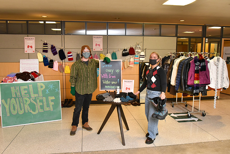 Sustainability Office interns Jonathan Mills, a graduate student in art, and Sarah Smelko, a senior global studies major, show off some of the free winter clothing offered in Hewitt during an ongoing free winter Warm-up Week clothing and gear giveaway