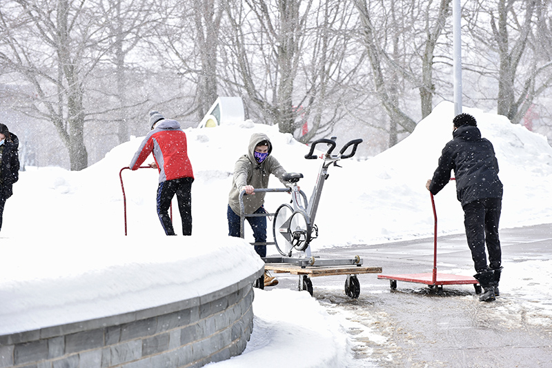 Student workers move exercise equipment to the new temporary home of the Fitness Centers in Marano Campus Center