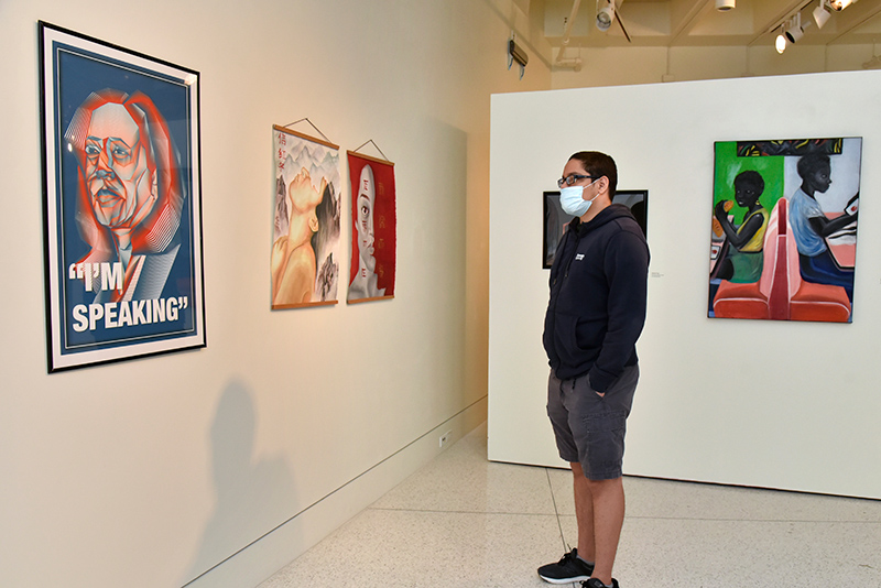 Emilio Jimenez, a freshman graphic design major and a Tyler Art Gallery attendant, looks at work on exhibit in the 58th annual Juried Student Art Exhibition