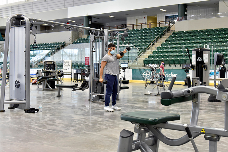 Erik Vergara, a senior finance major, works with some of the exercise equipment in Marano Campus Center Arena that was temporarily moved from Cooper in order to proved greater, more socially distanced space