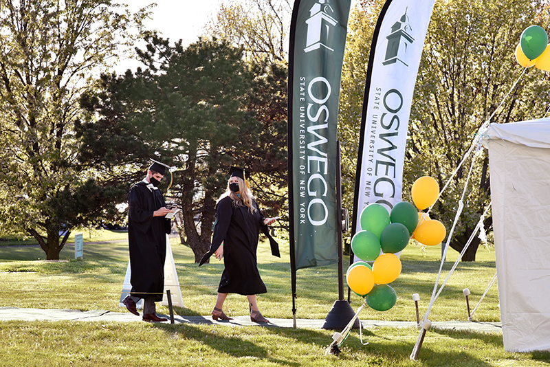 Students earning graduate degrees walk May 14 to the check-in tent on the north lawn of Marano Campus Center before their ceremony in the building's convocation hall and arena. 