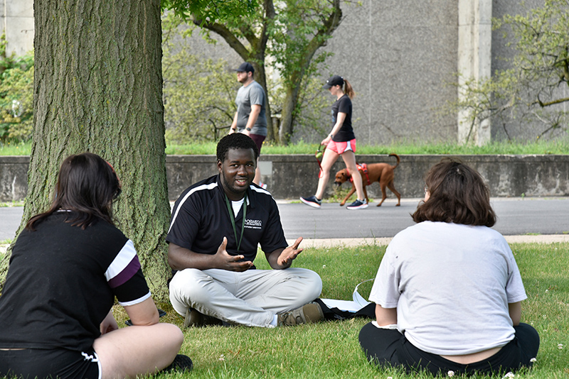 Laker Leader captain Yahya Ndiaye (center), a dual major in electrical and computer engineering and in French, sits in the quad between Hewitt and Penfield Library on July 7 with freshmen Adora Gorman (left), a zoology major, and Lily Polcovar-Horn, a psychology major.