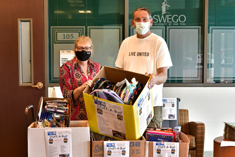 Cathy Johnston, assistant to the provost at and member of the State Employees Federated Appeal Planning Committee, and Patrick DeWine from the United Way of Greater Oswego County, display some of the school supplies collected during the SEFA’s annual Stuff A Bus drive which provides supplies to support school children around Oswego County.