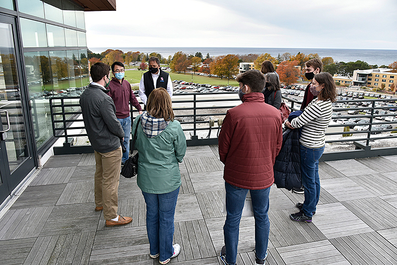 During Fall Open House, senior meteorology major Matthew Rolph (left) talks with a group interested in the meteorology program as he leads them through Shineman Center labs and classroom, including a view  from the Observation Deck of the campus Lake Ontario shoreline with Yonggang Wang (second from left) of the atmospheric and geological sciences faculty.
