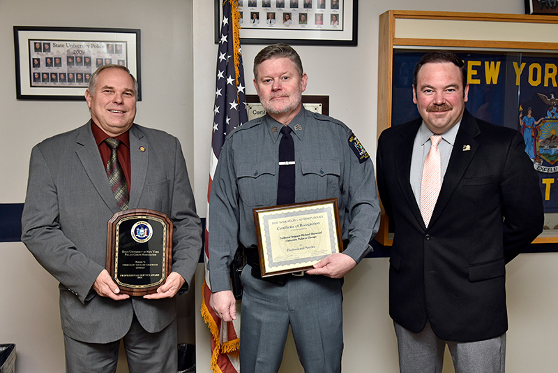 University Police Technical Sergeant Richard Sherwood was named recipient of a 2021 SUNY University Police Professional Service Award, which honors officers state-wide for demonstrating heroism and professional commitment to public safety. Sherwood, pictured in center, is congratulated by SUNY Oswego University Police Chief Kevin Velzy (left) and Assistant Chief Scott Swayze.