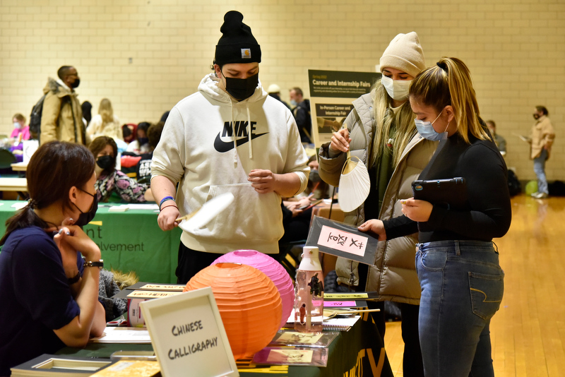 This semester's Student Involvement Fair held Feb. 2 in Swetman Gym showcased some of the hundreds of student clubs and organizations open to all students. Pictured are Student Association Programming Board (SAPB) members checking out the Chinese calligraphy created by Phoebe Kan (seated left) from NY Party Works. Using paper fans to air dry the freshly inked calligraphy are, standing from left: Aiden Burns, Isabelle Sherman and Yadi Aranda Burgos.