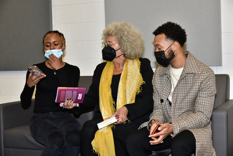 Oswego's 33rd annual Martin Luther King Jr. Celebration keynote speaker Angela Davis, center, signs copies of her book for senior Ziya Myers, who introduced Davis to the audience during the Feb. 9 event, and Marquél Jeffries of the Institute