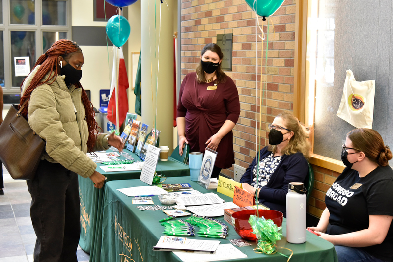 Djeneba Kante (standing at left), a sophomore global and international studies major, talks with Oswego's Education Abroad representatives, at table from left: Allison McGinley, education abroad secretary; Lyn Blanchfield, history department faculty member and scholarship adviser; and Destiny Crossway, student worker.