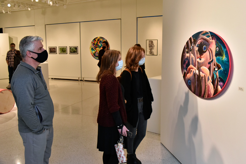 Shannon Reals, right, looks on with her parents at her oil painting titled “Graveyard of Giants” included in the 59th Annual Juried Student Art Exhibition.