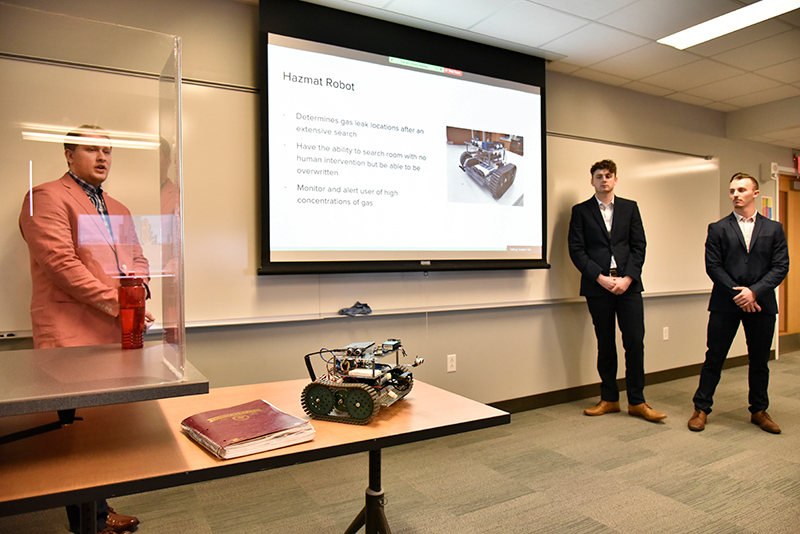 Electrical and computer engineering students, from left, Jesse Smithers, Christian Mackey and Anthony Ficarrotta explained specifics about their semi-autonomous robot that detects hazardous gasses in a presentation in the Shineman Center during Quest. The team designed, constructed and programmed the device as their capstone project. 