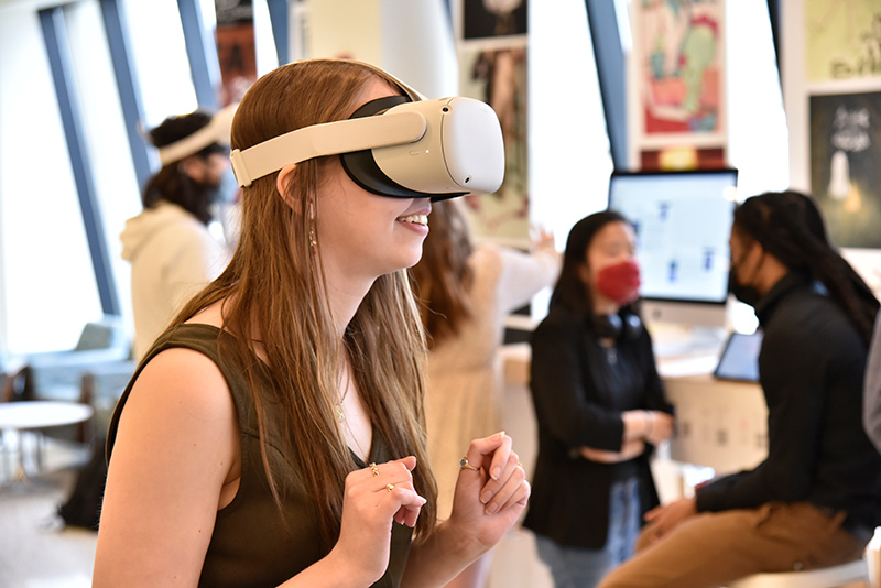 Ellen Weber, a graphic design major, experiments in a game environment with VR goggles in Tyler Hall lobby during Quest. The project was part of “Special Topics in Virtual Reality.”