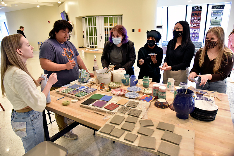 Demonstrating ceramic underglazes during a Quest presentation in Tyler Hall lobby are bachelor of fine arts and master’s in art teaching prep students Miranda Smith (left) and Aruasy Barrios (fourth from left). Underglazes are relatively low-temperature glazes that will later receive a glaze coating in ceramic making marbling technique.