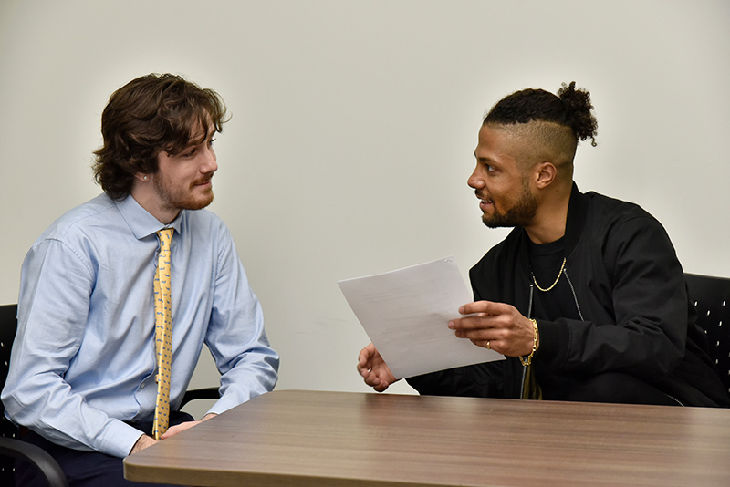 SUNY Oswego hosted a community conversation in Marano Campus Center auditorium April 12 with featured guest Mateo Askaripour, author of The New York Times best-selling "Black Buck." The public event examined corporate culture, racial justice and inclusive workspaces. Askaripour, pictured at right talking with senior Mitchell Farrar during a meeting in Wilber Hall, earlier that day visited faculty and students in the School of Business.