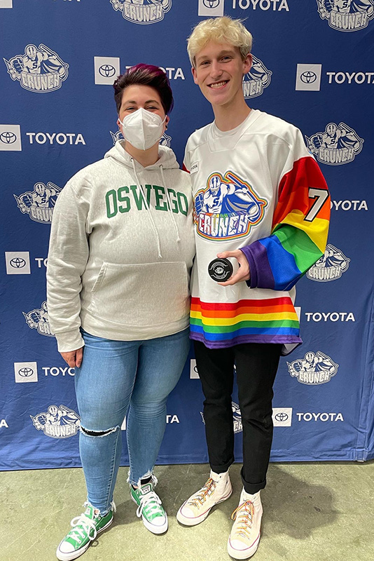 Admitted student Tyler Johnson (right) of Tully High School dropped the puck at the Syracuse Crunch Pride Night game on Saturday, April 24. Johnson is already known for his activism on behalf of LBGQT+ issues. SUNY Oswego Communications Manager Alex Dukat was on hand to support and document this memorable moment for a member of the Class of 2026.