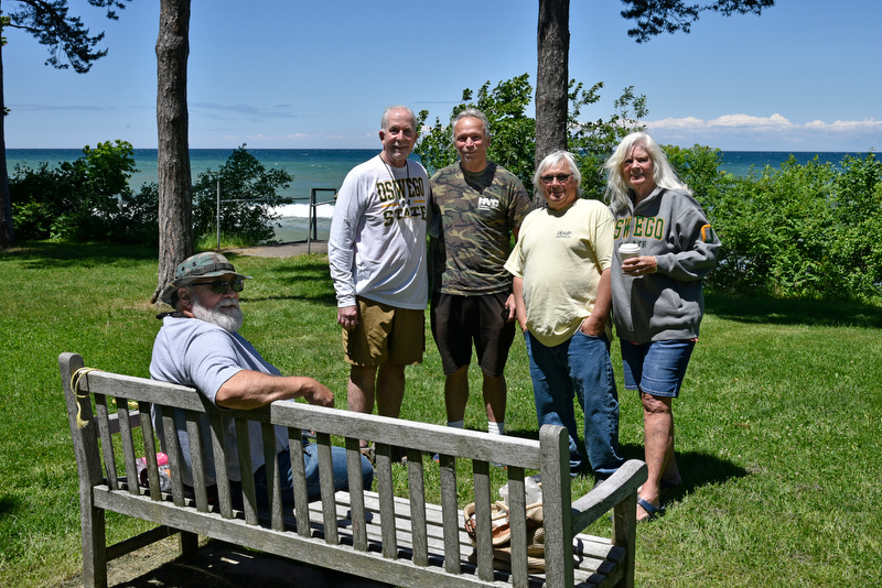 Friends gather at a campus bench overlooking the lake behind Riggs Hall after checking in for Reunion Weekend, held June 9 to 12.