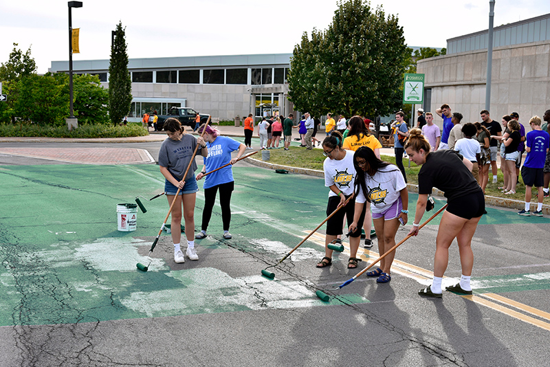 Students painting the Marano Campus Circle green 